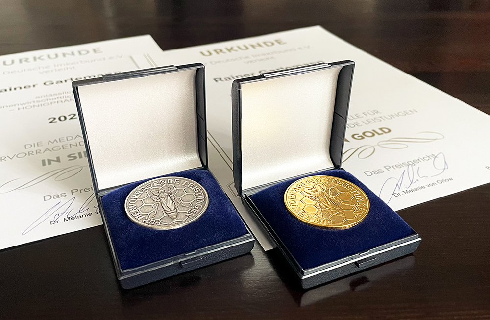 Gold- und Silbermedaille im offenen Schmuckkästchen auf Urkunden.